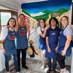 group of baristas gathered in front of a colorful mural
